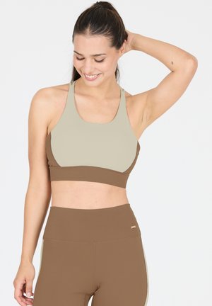 Sportbeha en legging set in lichtbeige en bruin. De beha heeft een ronde halslijn en brede bandjes; de legging heeft een hoge tailleband.