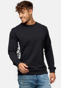 Sort sweatshirt med lange ærmer, rund hals og hvide sidelommer med tekst. Lavet af blødt materiale med en klassisk pasform.
