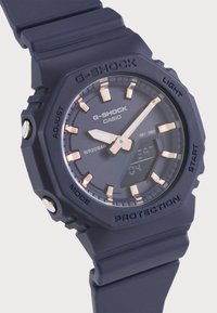 Orologio G-Shock blu con display digitale, dettagli in oro rosa e cinturino in silicone testurizzato. Presenta pulsanti per le funzioni di regolazione e luce.