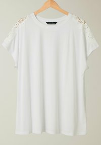 T-shirt bianco a maniche corte con dettagli in pizzo sulle spalle, caratterizzato da un collo rotondo e una vestibilità rilassata, realizzato in tessuto morbido.