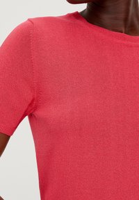 Rosa stickad kortärmad tröja med rund halsringning, slät textur och subtil ribbning vid ärmarna och nederkanten. Inga synliga mönster eller fästen.