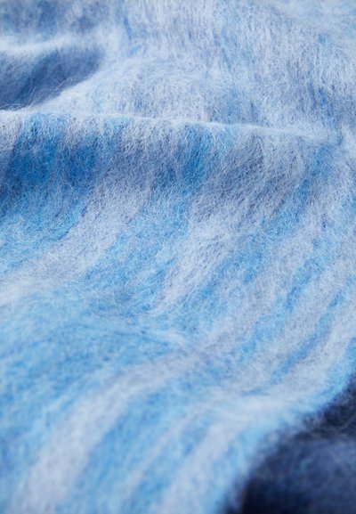 Hellblau und weiches Wollgewebe mit einer leicht flauschigen Textur, das in verschiedenen Blautönen durchzogen ist.