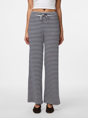 Pantalons larges à rayures navy et blanches, dotés d'une taille à cordon, d'une texture côtelée douce et d'une coupe décontractée. Chaussures plates portées.