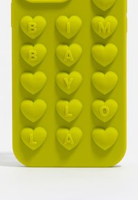 Żółty silikonowy futerał na telefon z wypukłymi kształtami serc, na których znajdują się litery tworzące słowa "BABY" i "LALA". Gładka tekstura i zaokrąglone narożniki.