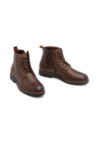 Botas de piel marrón hasta el tobillo con cordones en la parte delantera y cremallera lateral, con una superficie texturizada, puntera redonda y suela de goma con agarre.