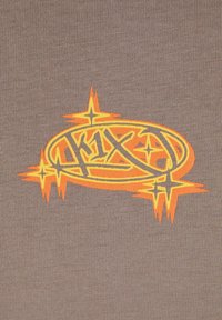 Brun tekstil har et fremtredende grafisk logo i gult og oransje med stjernemotiv og intrikate linjer, satt mot en teksturert bakgrunn.