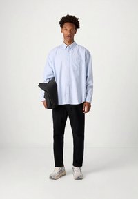 Šviesiai mėlyna marškinėliai su krūtinės kišene, juodos kelnės ir juoda rankinė. Aprangą užbaigia pilki ir balti sportbačiai.