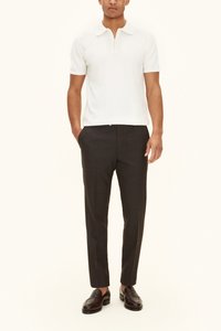 Valkoinen lyhythihainen poolopaita vetoketjukauluksella, yhdistetty tummanharmaisiin räätälöityihin housuihin ja ruskeisiin nahkaisiin slip-on-kenkiin.