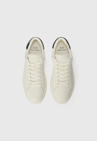 Witte leren sneakers met een gladde afwerking, voorzien van een zwarte hielkap, vetersluiting aan de voorkant en branding op de tong en zijkant.