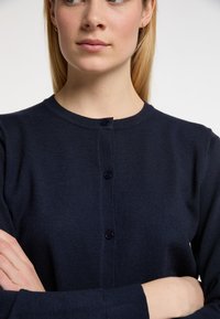 Cardigan blu navy in morbido tessuto a maglia, con scollatura rotonda e cinque bottoni scuri davanti, con polsini e orlo a costine.