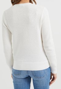 Bílý svetr s texturovaným úpletem, kulatým výstřihem, žebrovanými manžetami a lemem. Vzor tvoří malé diamantové tvary po celém svetru.