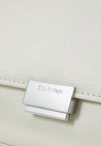 Calvin Klein ARCHIVE SHOULDER BAG SHINY - Bolso de mano - ecru