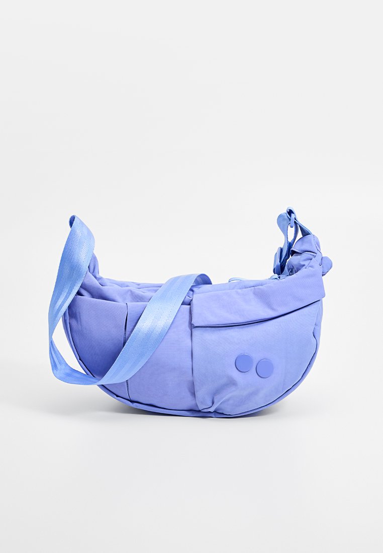 Purple fabric bag with a rounded shape, adjustable strap, and two circular accents. Smooth texture with zippered compartments.