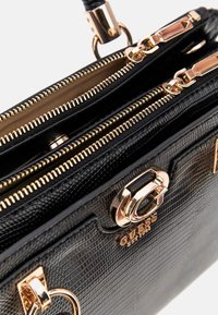 Borsa sintetica nera con texture e dettagli dorati, compartimenti con doppia zip e logo. Presenta un design elegante con una forma strutturata.