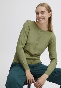 Cardigan en tricot vert avec un col rond et une fermeture à boutons. Présente un design ajusté et des poignets côtelés. Texture lisse et aspect doux.