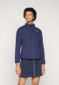 Navy zip-up jacket by Calvin Klein, featuring a high collar, elastic cuffs, and a slightly fitted design. Smooth texture and lightweight.