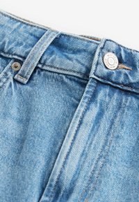 Světle modré džíny z denimu s knoflíkovým zapínáním, kontrastním oranžovým prošíváním a hladkou texturou. Obsahují pas s poutky na pásek.