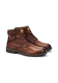 Botas de cuero marrón hasta el tobillo con punta circular, cuello de ante marrón en contraste, diseño con cordones y detalle de hebilla en el costado.