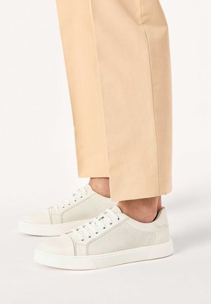 Valged tossud siledast nahast, perforatsiooni ja kummist talla ning heledate beežide kohandatud pükstega.