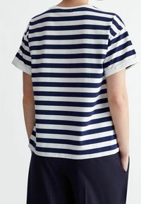Camiseta de rayas en navy y blanco con mangas cortas, cuello redondo y dobladillos de las mangas enrollados. La tela parece suave y transpirable.
