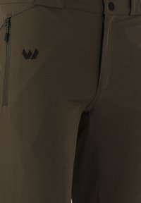 Donkergroene softshellbroek met verborgen ritszak en zwart logo nabij de heup, met knoopsluiting en gestikte naden.