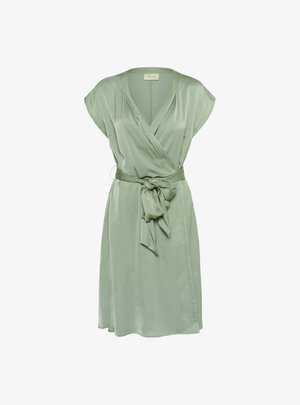 Groene wikkeljurk van zijdeachtig materiaal, met korte mouwen, een strikband in de taille en een vloeiende silhouet.