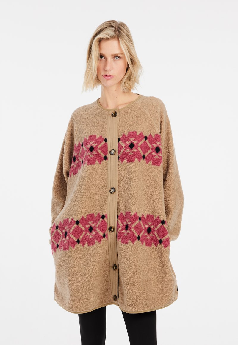 Beige fleecedeken met een bloempatroon in roze en zwart, voorzien van een knoopsluiting aan de voorkant en een comfortabele pasvorm. Zachte textuur en lange mouwen.