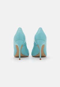 Turquoise high-heeled shoes with a smooth leather texture, pointed toes, and slender stiletto heels. Features subtle side cutouts.