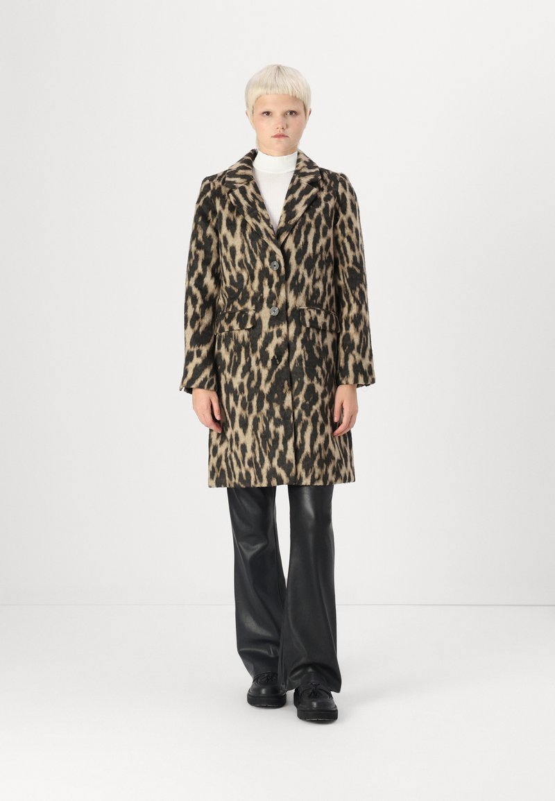 Abrigo de lana con estampado de leopardo, con cuello, dos botones y bolsillos frontales; combinado con pantalones de cuero negro y zapatos.