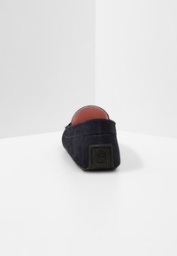 Chaussure en suede marine à enfiler avec un dos bas, un bout arrondi et une semelle en caoutchouc noire. Présente un doublure intérieure rose et des détails de couture minimalistes.