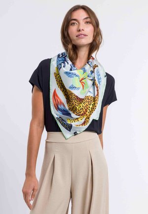 Vierkante zijden sjaal met een luipaardprint en kleurrijke bloempatronen, omrand met een groene rand, gedragen over een zwarte top.