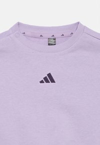 Sweatshirt în nuanță de violet deschis, cu guler rotund, gât ribetat și un accent de logo închis pe piept. Material moale, cu o textură netedă.