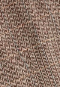 Tissu chevrons marron et beige avec de fines rayures bleues et orange, motif tissé en laine texturée.