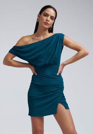 Teallin off-shoulder-mekko, joka on valmistettu teksturoidusta kankaasta, istuu vyötäröltä tiiviisti, ja siinä on sivuhalkio sekä poimuttaminen hameessa.