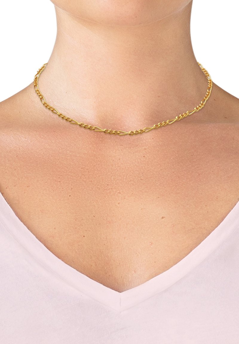 Collier chaîne en or avec des maillons torsadés porté sur un cou nu au-dessus d'un haut rose clair à col en V.