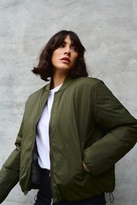 Olive roheline pommitusjakk, millel on lõpp, küljetaskud ja soonikkoes äär. Kandsin seda valge särgi peal, neutraalse taustaga.