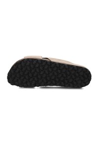 Tan suède schoen met een zwarte rubberen zool met een golvenpatroon. De schoen heeft een plat, breed ontwerp dat geschikt is voor casual gebruik.