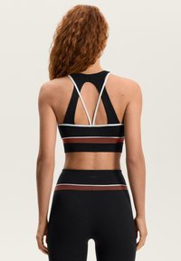 Čierna športová podprsenka s dizajnom racerback a viacfarebnými horizontálnymi pruhmi v hnedej a bielej farbe. Vyrobená z textúrovanej, elastickej látky.