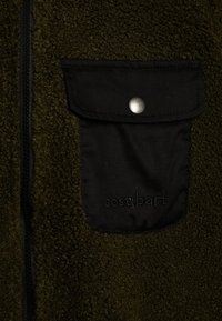 Casaco de fleece em verde oliva, com um bolso de tecido preto com botão de pressão e logótipo em relevo, e um fecho éclair em contraste.