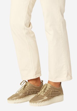 Lichtbeige gebreide sneakers met dikke witte geribbelde zolen, gedragen bij gebroken witte broek.