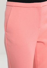 Roze op maat gemaakte broek met een gladde textuur, voorzien van zijzakken en een vlakke voorkant. De stof lijkt lichtgewicht en iets rekbaar te zijn.