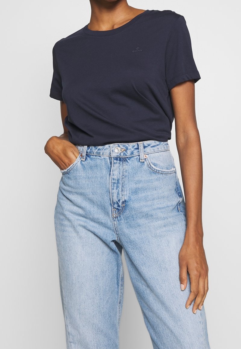 Navy blue cotton t-shirt with a crew neckline and short sleeves, paired with high-waisted light blue denim jeans with a relaxed fit.