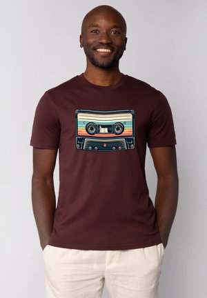 Bordeaux T-shirt met een retro cassettebandje graphic in blauw, geel en roze. Korte mouwen en een ronde hals.