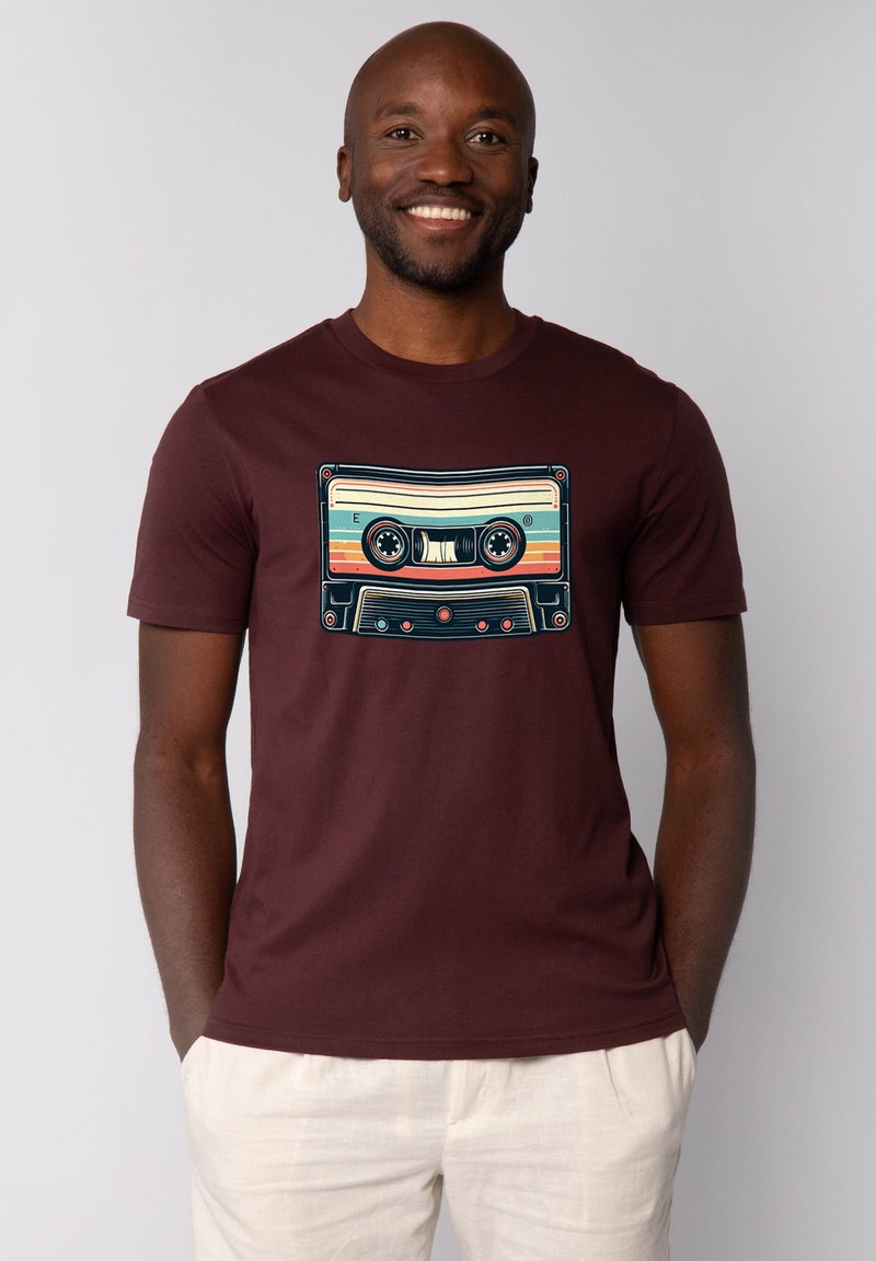 T-shirt bordeaux avec un motif rétro de cassette audio en bleu, jaune et rose. Manches courtes et encolure ronde.