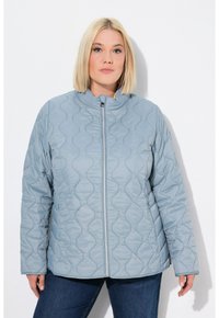 Chaqueta acolchada de color azul claro con cuello alto, que presenta un cierre frontales y un patrón hexagonal. El cuello interior es de color amarillo.