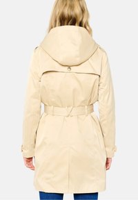 Béžový nepromokavý trenčkot s páskem a kapucí, s ventilačním rozparkem na zádech a knoflíkovými detaily. Jemná látka s elegantním, štíhlým střihem.