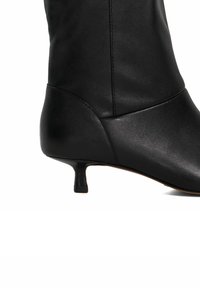 Black leather ankle boot with a sleek shape, featuring a small, flared heel and minimalistic design with smooth texture.