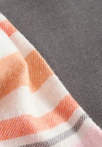 Cotton fabric in gray with a soft, textured finish; edged by a striped pattern of orange, white, and gray in a smooth knit.