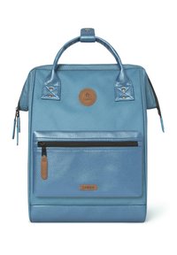 Zaino blu con materiale testurizzato, manici lucidi, tasca frontale con zip e una toppa a forma di cerchio. Presenta un design elegante e accenti in contrasto.