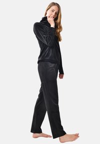 Black velvet loungewear set featuring a high collar top and straight-leg pants. Soft texture and seamless design offer comfort and style.